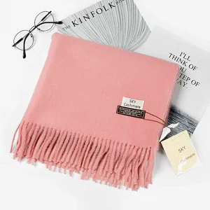 Detailansicht eines weichen rosa Kaschmirschals mit eleganten Fransen und Markenetikett.