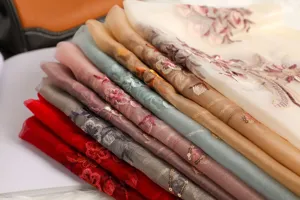 Close-up detail of luxurious sheer silk embroidered floral shawl with delicate sequin accents.