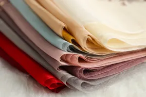 Close-up detail shot of multi-color sheer silk fabric scarves stacked neatly together.