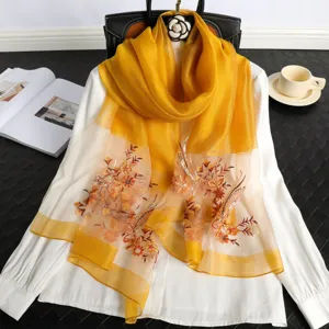 Detailed view of yellow silk floral embroidered scarf shawl, elegant accessory display.