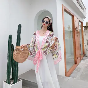 Stylish resort sun protection cape set with coral pink floral scarf and elegant white dress for beach.