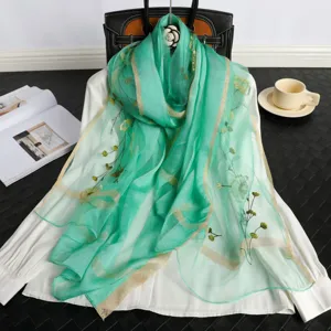 Green embroidered silk scarf with elegant gold border and delicate floral patterns.