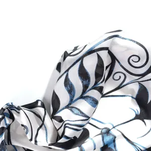 Close-up detail of lightweight women's printed silk scarf with elegant black and blue leaf pattern.