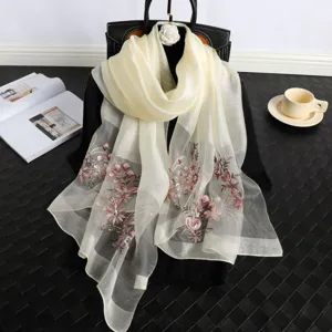 Detailed view of elegant beige sheer silk scarf with delicate floral embroidery and sequins.
