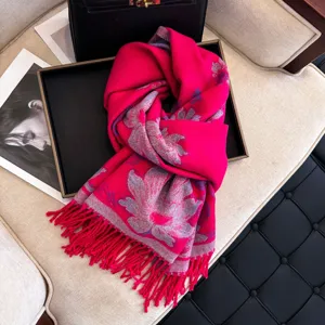 Close-up detail of a bright pink winter scarf with floral jacquard pattern and long tassels.