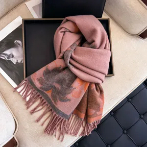 Close up of a thick winter jacquard women scarf with fringe, elegant floral design in pink and orange.