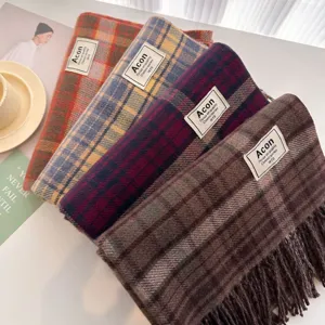 Detailed close-up of cozy plaid winter scarves in assorted colors with fringe and brand label.