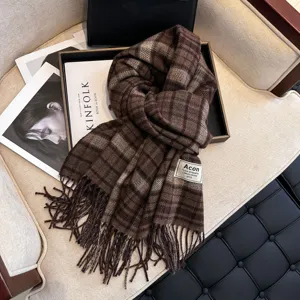 Close-up detail of a cozy brown plaid scarf with fringe, featuring textured woven fabric in a chic autumn style.