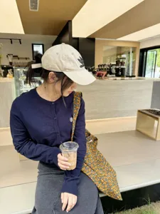 Detailed lifestyle shot of a floral canvas shoulder bag worn by a model in a cafe setting.