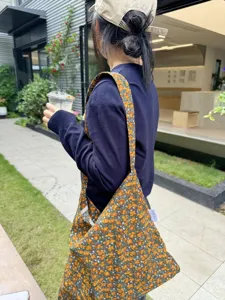 Detailed shot of retro floral shoulder canvas bag worn outdoors, showing stylish floral pattern.