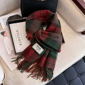 Close up view of cozy red green plaid winter tassel scarf with classic brand logo label detail.