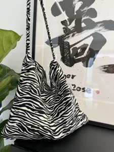 Closeup detail of stylish black and white zebra print canvas shoulder bag, soft textured fabric.