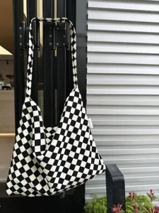 Detail shot of black and white checkerboard canvas tote bag, showing fabric texture and style.