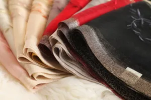 Close-up detail of luxurious silk wool blend embroidered scarf with metallic trim.