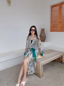 Green tropical leaf print long summer beach cover-up cardigan with tie belt detail worn by model.