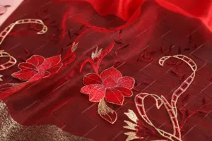 Close-up detail of red silk wool blend scarf featuring exquisite red and gold floral embroidery.