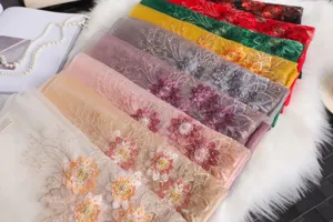 Vista detallada de pañuelos de seda coloridos con bordado de cuentas florales y textura fina.