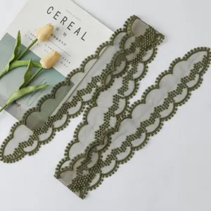 Détail de ruban en dentelle vert olive avec un motif floral ondulé ajouré exquis.
