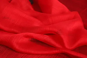 Detailed close-up view of a luxurious red silk scarf fabric, showing delicate texture and soft drapery.