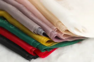 Pila de bufandas de seda transparente de colores con textura ligera y delicada.