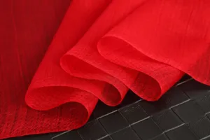 Detailed close-up of red textured scarf fabric showcasing soft drape and fine weave.
