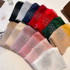 Vue détaillée de foulards en soie artificielle avec perles et strass aux motifs floraux.