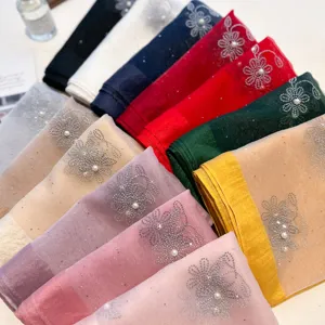 Detailed close-up of colorful silk scarves with exquisite rhinestone floral and pearl bead embroidery.