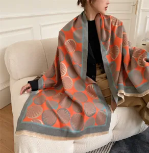 Detailaufnahme eines eleganten orangen gemusterten Kaschmir-Gefühl Schals auf Sofa.