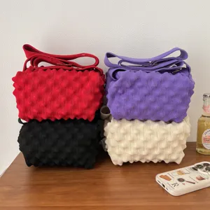 Detailed view of candy color knitted shoulder bags in red, purple, black, and beige.