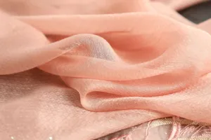 Close-up detail of luxurious pink silk scarf fabric showcasing fine texture and exquisite embroidery.