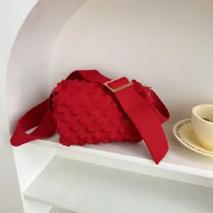 Red knit crossbody bag featuring wide strap and textured bubble design for daily commute.
