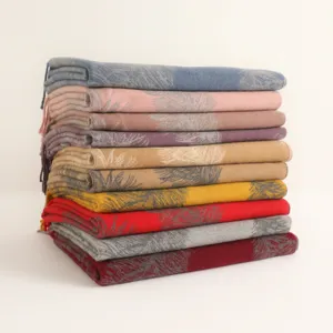 Close-up of stacked colorful cashmere winter scarves featuring delicate feather jacquard patterns.