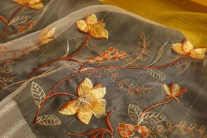 Detailed close-up view of luxury sheer silk scarf with delicate floral and leaf embroidery.