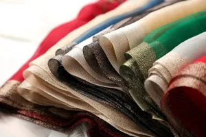 Detailed view of luxury silk scarves with metallic gold borders in vibrant assorted colors.