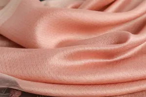 Detailed view of the luxurious peach silk wool scarf showcasing delicate fabric texture.