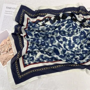 Detailaufnahme des blau-weißen Schals mit Leopardenmuster und elegantem Goldkettenrand.