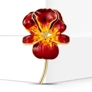 Primer plano de broche de flor de iris de esmalte vintage, detalles rojos y amarillos.