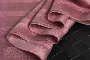 Nahaufnahme des rosa karierten Schals mit weicher Stoffstruktur und feinem Metallikgewebe.