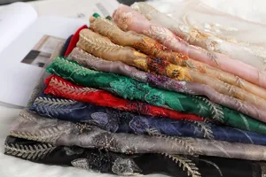 Eleganti sciarpe di seta ricamate impilate in vari colori brillanti con dettagli floreali.