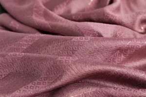 Detailaufnahme eines feinen Seidenschals mit geometrischem Webmuster und glänzenden Metallfäden.
