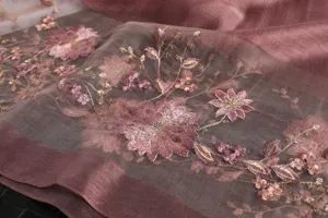 Close-up detail of sheer silk scarf with delicate pink floral and gold embroidery work.