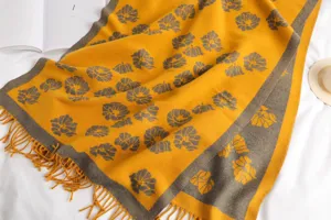 Detailed view of yellow and grey floral patterned winter scarf with soft tassels.