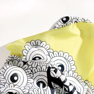Close-up detail of lemon yellow silk scarf with black and white graphic floral print fabric.