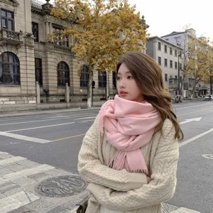 Gemütlicher rosa Fransenschal und warmer Strickcardigan in einer Straßenszene.