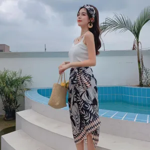 Summer resort poolside detail shot featuring stylish printed sarong, white camisole and straw bag.