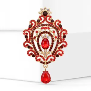 Prachtige goudkleurige broche met rode strass-steentjes en kristallen filigraandesign.
