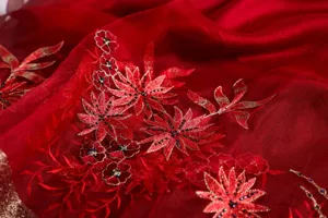 Detailed view of red silk scarf featuring exquisite floral embroidery and subtle sparkling bead accents.