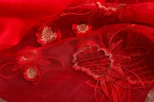 Detailed shot of red silk wool scarf with exquisite golden floral embroidery texture.