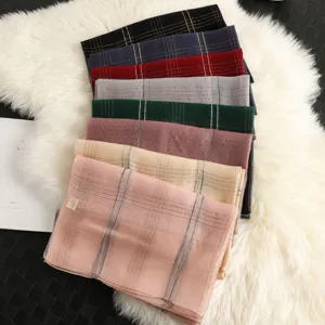 Detail view of colorful striped scarves with gold embroidery stacked neatly on fluffy rug.
