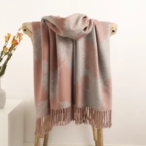 Detail shot of draped cashmere feel tassel scarf with feather pattern on wooden chair.